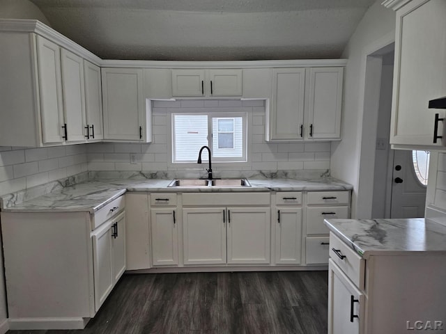 kitchen with light countertops, dark wood finished floors, white cabinets, and a sink