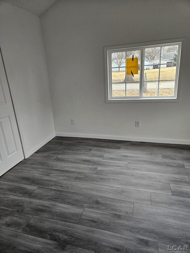 spare room featuring dark wood-type flooring and baseboards