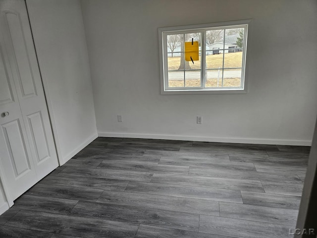 empty room featuring dark wood-type flooring and baseboards