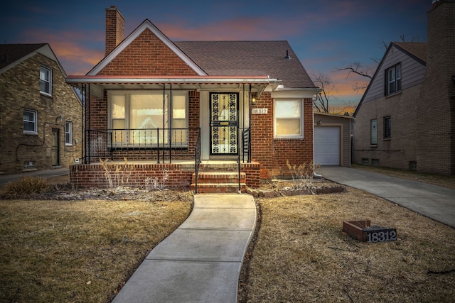 view of front of home with brick siding, a chimney, a porch, concrete driveway, and a garage