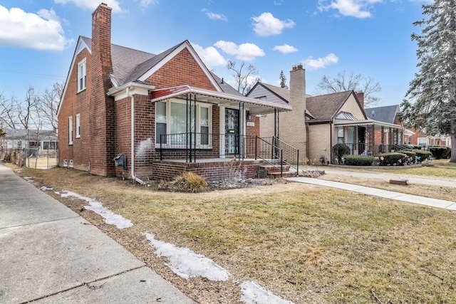 bungalow featuring covered porch, brick siding, a chimney, and a front lawn