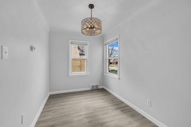 unfurnished dining area with baseboards, visible vents, and wood finished floors