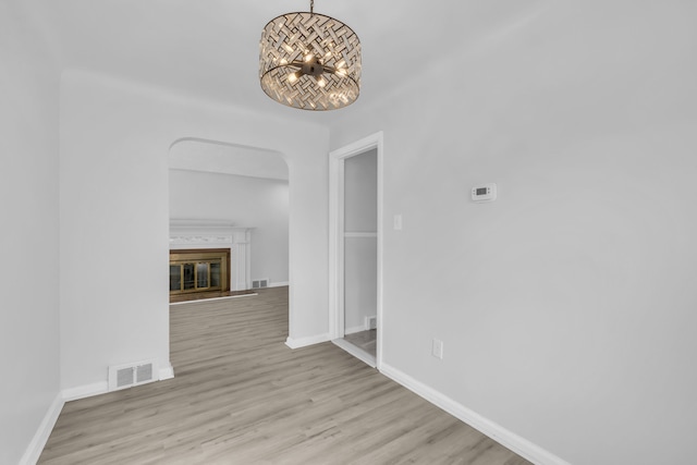 unfurnished dining area featuring an inviting chandelier, baseboards, visible vents, and wood finished floors