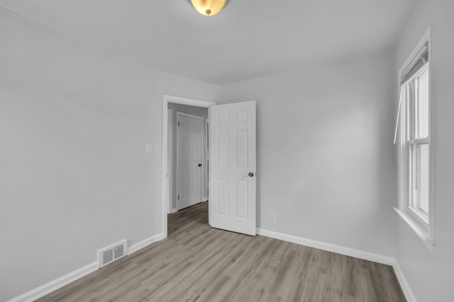 spare room featuring visible vents, baseboards, and wood finished floors