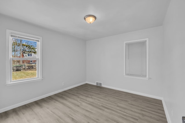 unfurnished room with visible vents, baseboards, and wood finished floors