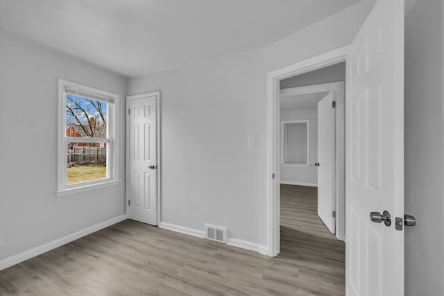 empty room featuring light wood finished floors, visible vents, and baseboards