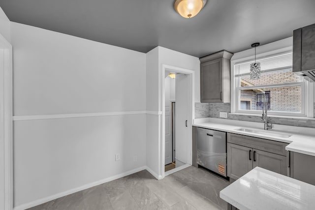 kitchen with gray cabinetry, a sink, baseboards, light countertops, and stainless steel dishwasher