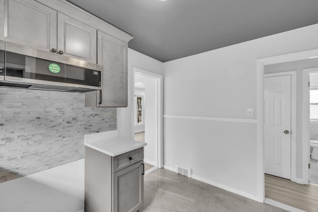 kitchen featuring visible vents, stainless steel microwave, light countertops, and baseboards