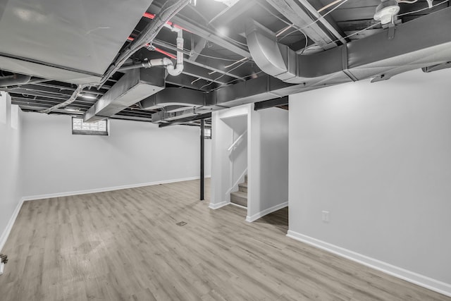 below grade area with stairway, wood finished floors, and baseboards