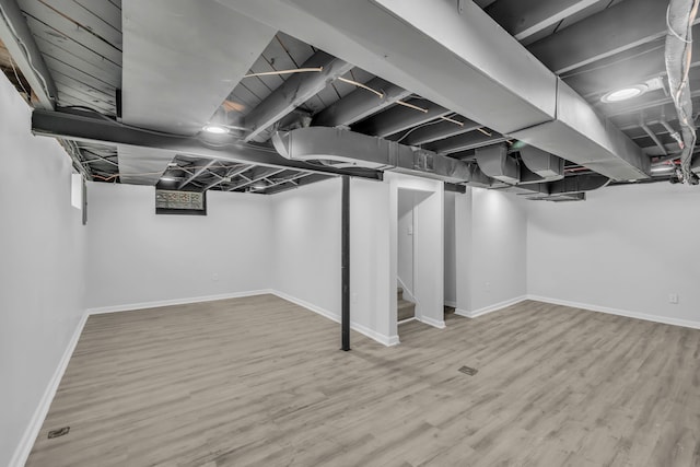 finished basement featuring stairs, wood finished floors, and baseboards