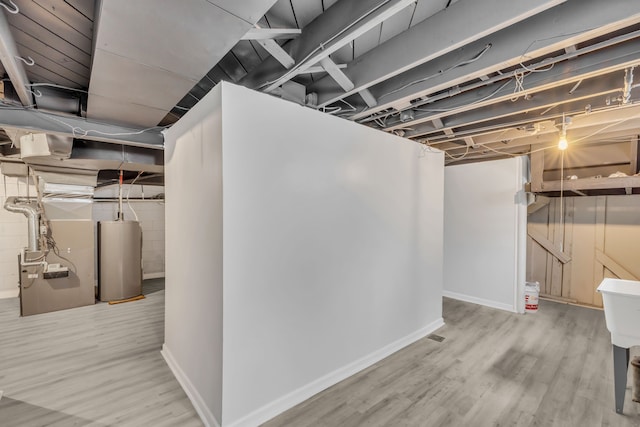 unfinished basement with water heater, baseboards, and wood finished floors