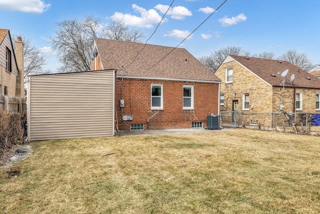 rear view of house with roof with shingles, brick siding, a lawn, central AC unit, and fence