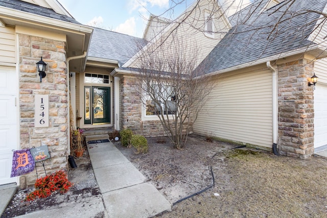 view of exterior entry featuring a garage, stone siding, and a shingled roof