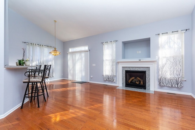 living area featuring wood finished floors, baseboards, visible vents, high vaulted ceiling, and a tile fireplace