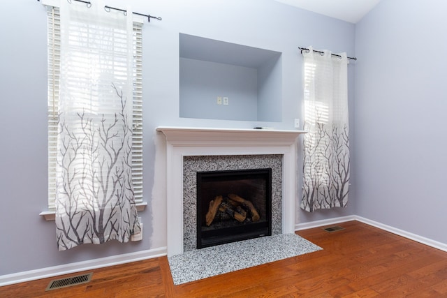 room details with visible vents, a fireplace with flush hearth, and wood finished floors