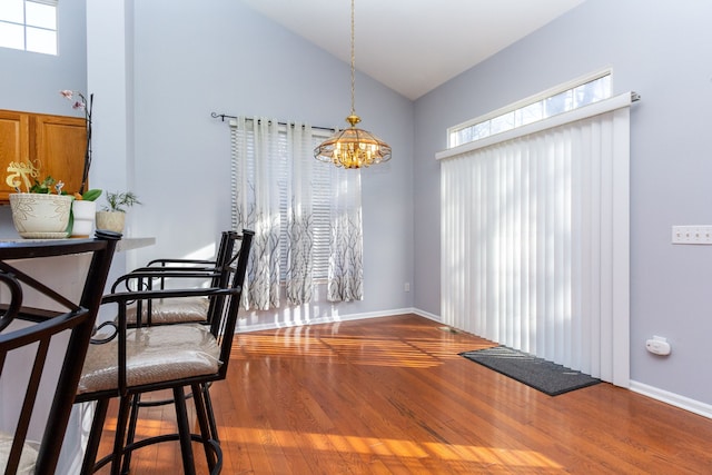 dining area featuring baseboards, plenty of natural light, high vaulted ceiling, and wood finished floors