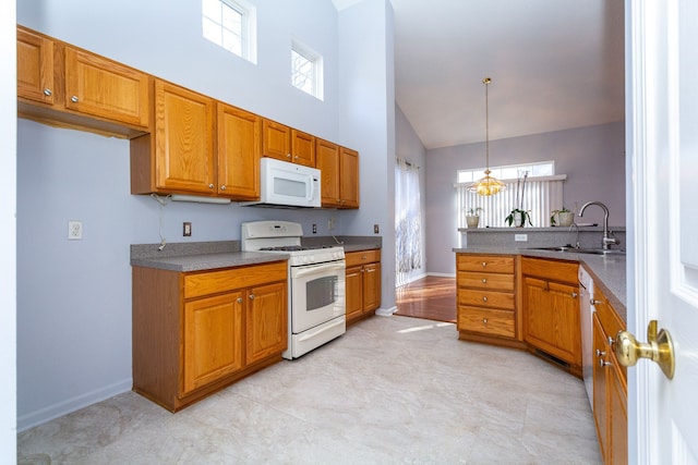 kitchen featuring decorative light fixtures, a high ceiling, brown cabinetry, white appliances, and a sink