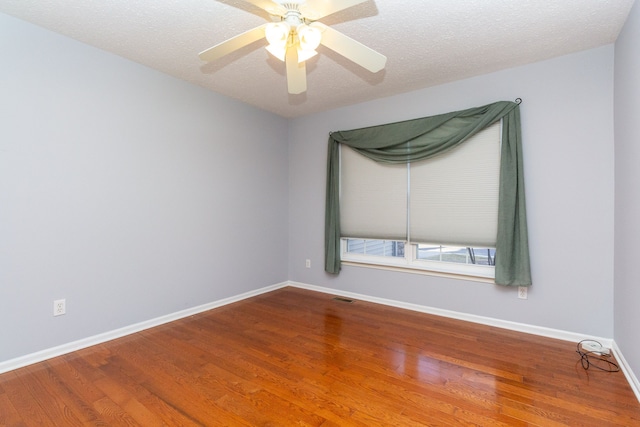 spare room with visible vents, ceiling fan, baseboards, wood finished floors, and a textured ceiling