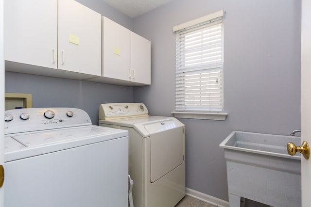 washroom with washer and dryer, cabinet space, baseboards, and a sink