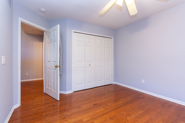 unfurnished bedroom with a ceiling fan, wood finished floors, baseboards, a closet, and a textured ceiling