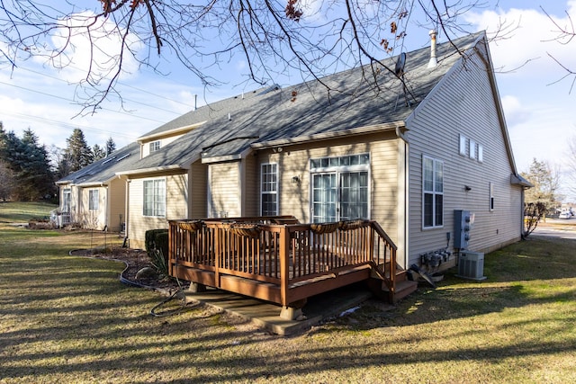 back of house featuring a deck, a lawn, roof with shingles, and central AC unit