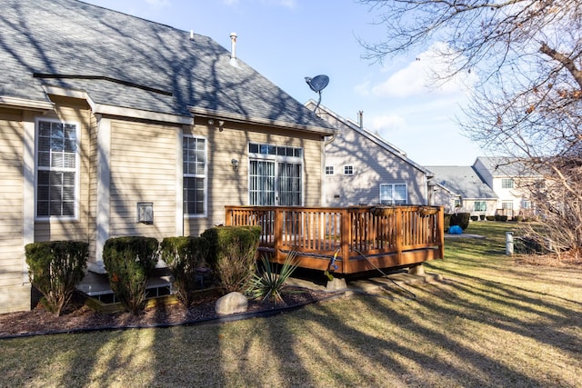 rear view of property featuring a deck, a yard, and roof with shingles