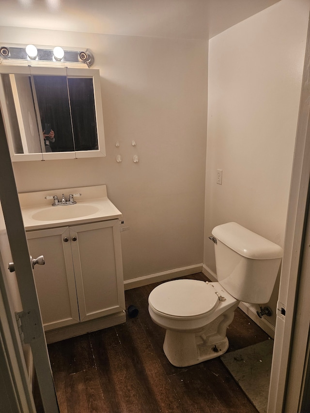 bathroom featuring toilet, baseboards, wood finished floors, and vanity