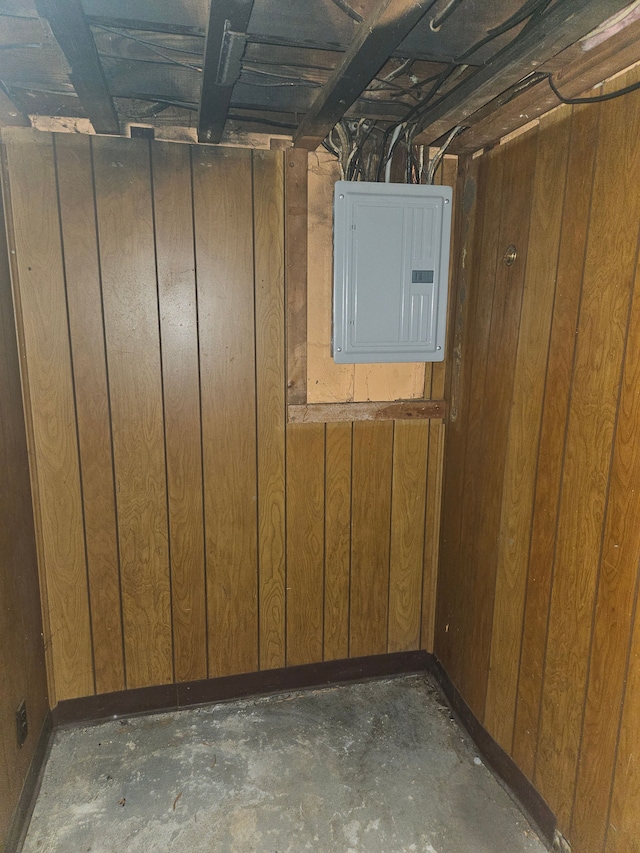 unfinished basement featuring wood walls and electric panel