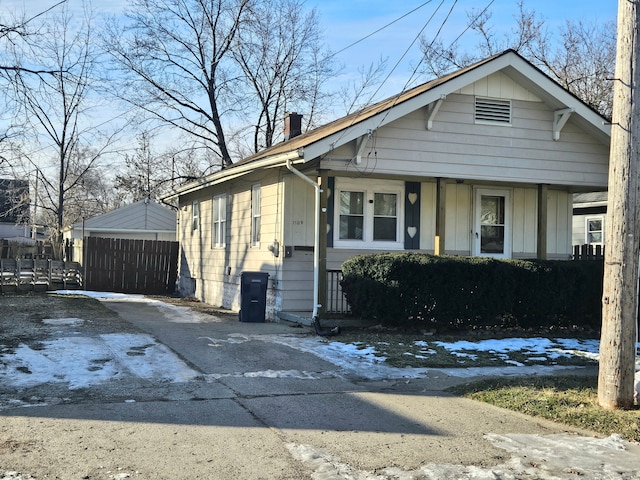 bungalow-style home with board and batten siding, a chimney, and fence