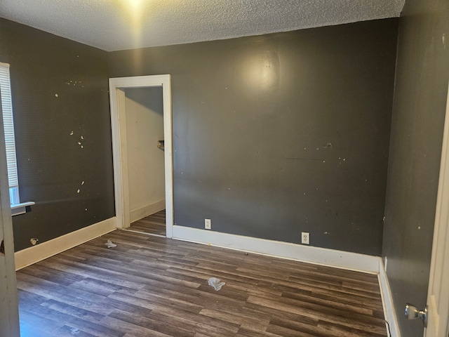 spare room featuring a textured ceiling, baseboards, and wood finished floors