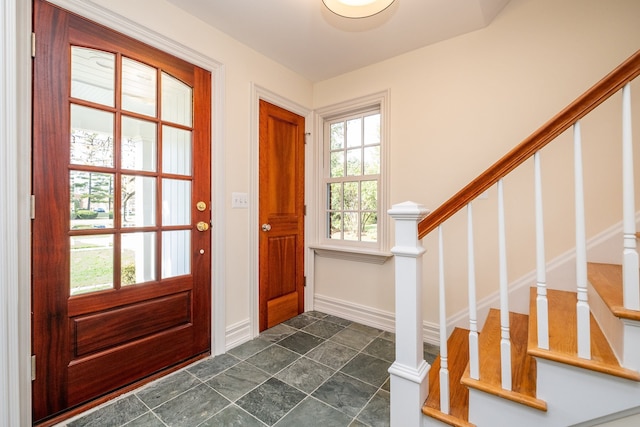 entryway with stone finish flooring, stairway, and baseboards