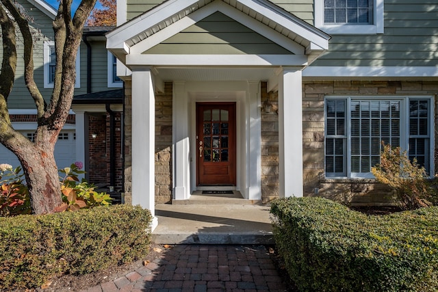 doorway to property with an attached garage, stone siding, and brick siding