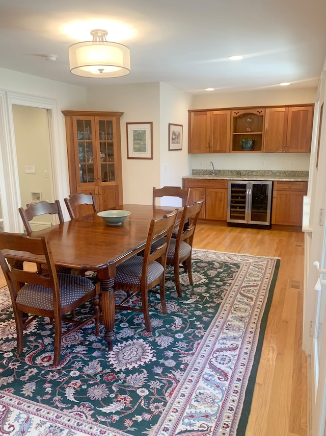 dining room with beverage cooler, light wood-type flooring, and wet bar