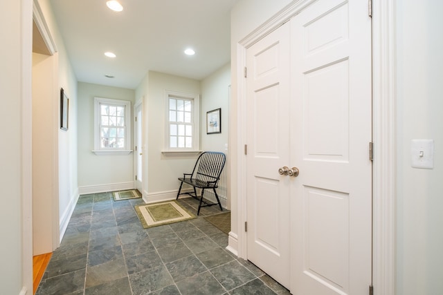 hallway featuring recessed lighting, stone finish floor, and baseboards