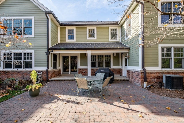 back of property featuring a patio, brick siding, central AC unit, and french doors