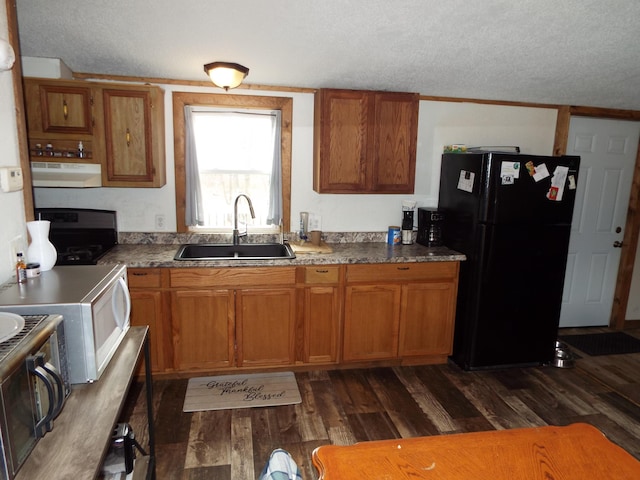 kitchen featuring white microwave, dark wood-type flooring, freestanding refrigerator, a sink, and under cabinet range hood