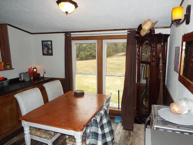 dining space featuring a textured ceiling, wood finished floors, and crown molding