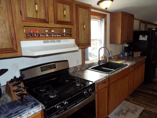 kitchen featuring brown cabinets, gas stove, a sink, and under cabinet range hood