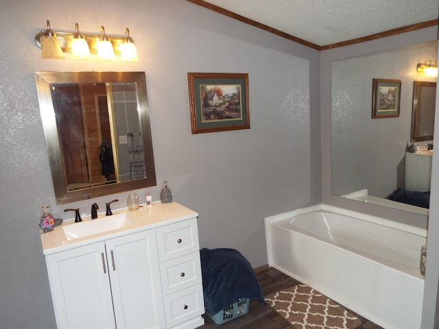 full bathroom featuring a textured ceiling, vanity, wood finished floors, and a bath