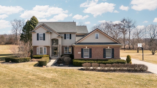 traditional home with brick siding, roof with shingles, and a front yard