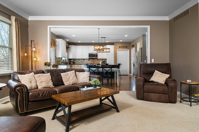 living area with crown molding, a notable chandelier, baseboards, and visible vents