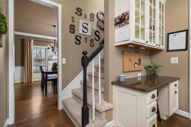 staircase featuring an inviting chandelier and wood finished floors