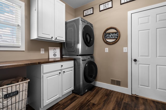 washroom with visible vents, dark wood-type flooring, baseboards, stacked washing maching and dryer, and cabinet space