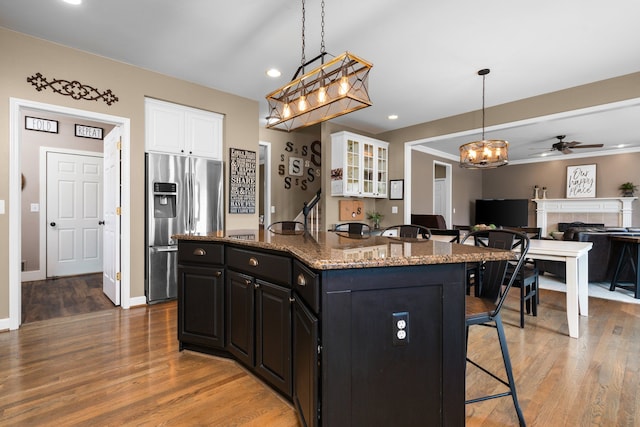 kitchen with a breakfast bar, white cabinets, stainless steel fridge with ice dispenser, and dark cabinets