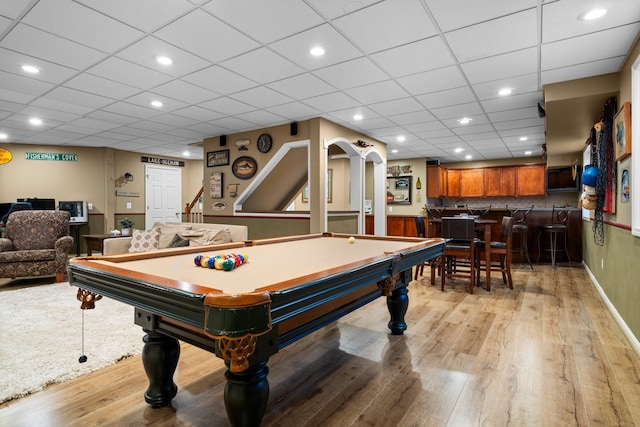 rec room with billiards, a wainscoted wall, light wood finished floors, recessed lighting, and bar area