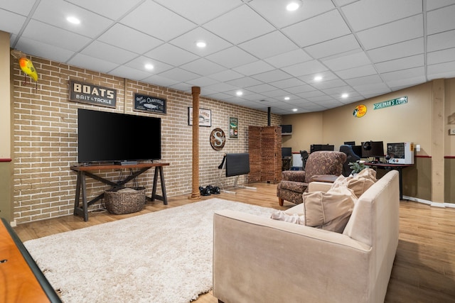 living room featuring recessed lighting, a drop ceiling, wood finished floors, and brick wall