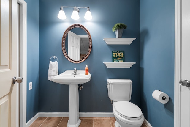 half bathroom with tile patterned floors, toilet, and baseboards