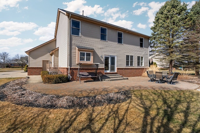 back of property featuring a patio, brick siding, a lawn, and entry steps