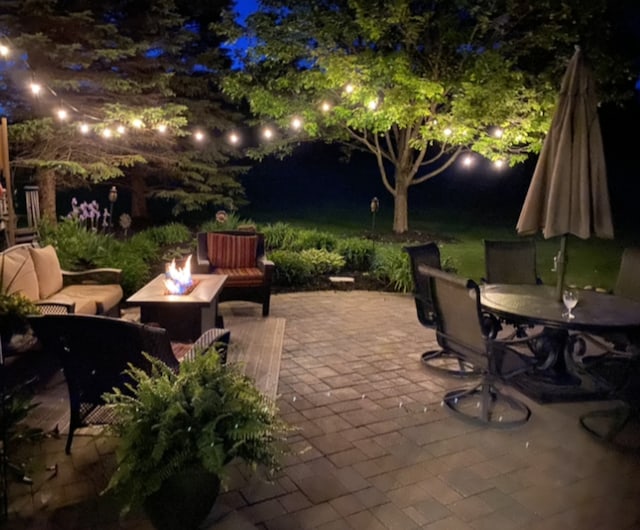 patio at night with a fire pit and outdoor dining space