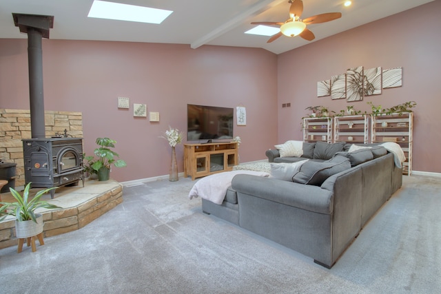 living area with ceiling fan, baseboards, a wood stove, and light colored carpet